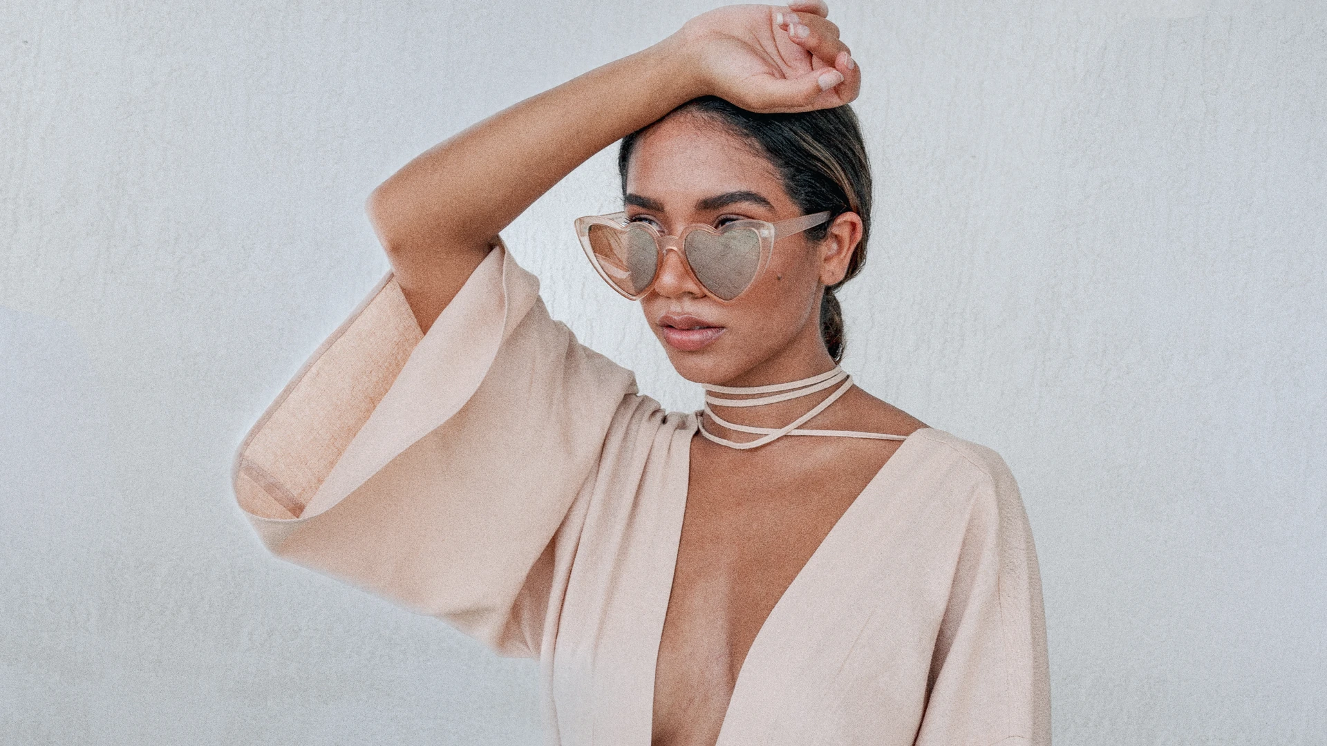 Woman in heart-shaped sunglasses and a blush kimono, hand on her head
