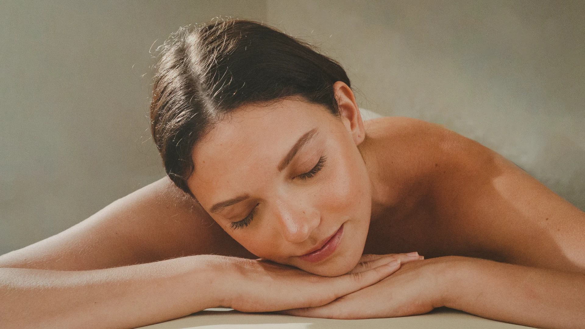 Woman resting her head on her hands, eyes closed, in soft window light